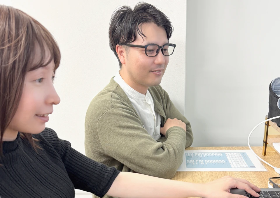 写真:モニターを見ながら作業している女性スタッフと横に座っている男性スタッフ